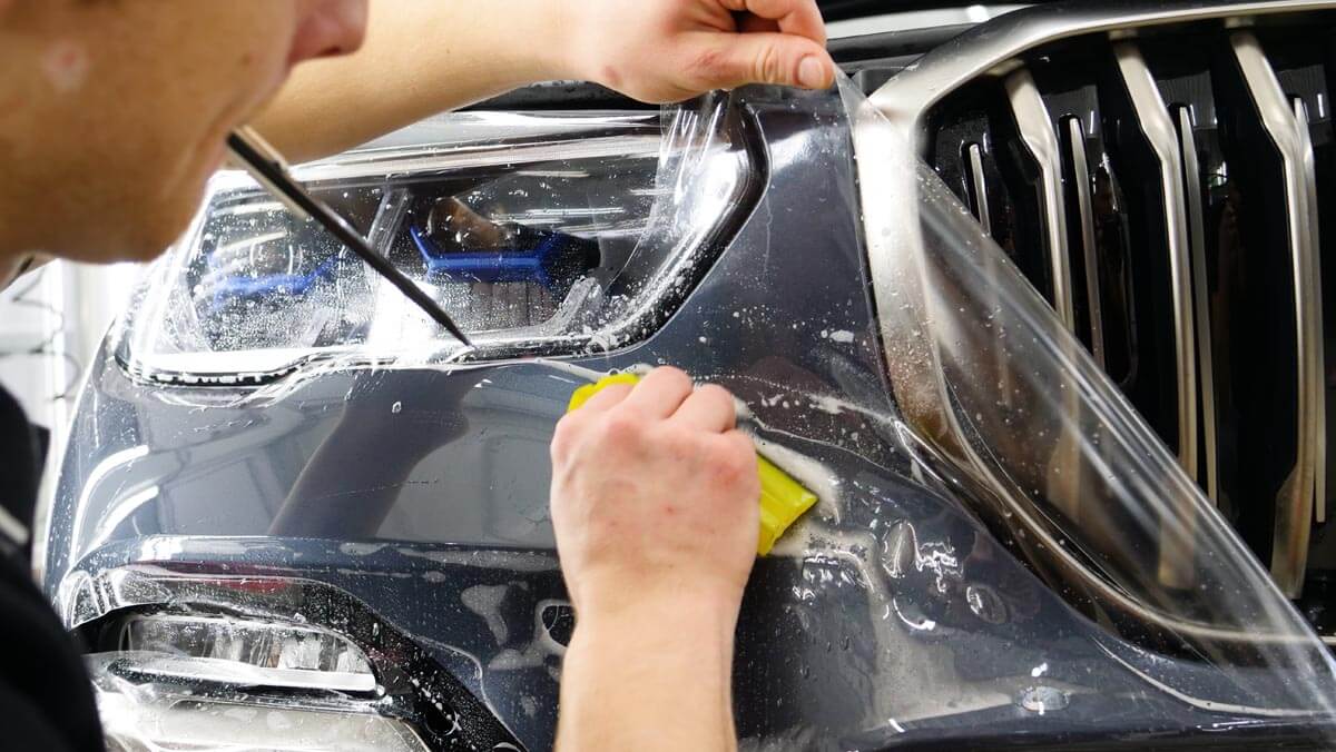 Technician installing PPF on bumper.