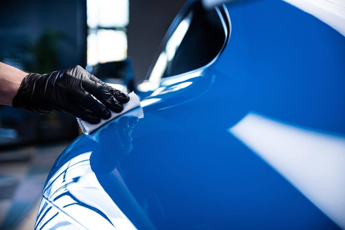 Technician installation a coating on a Blue Porsche.